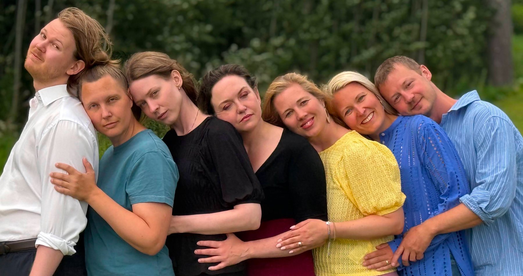 Slams sju improvisatörer står tätt ihop utomhus framför grönska